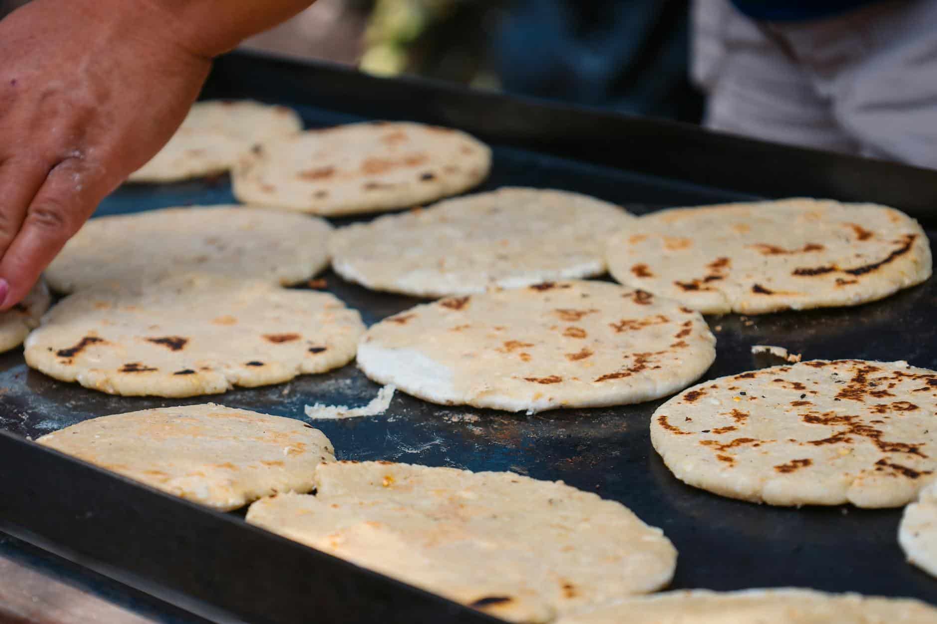 homemade arepas on griddle being prepared