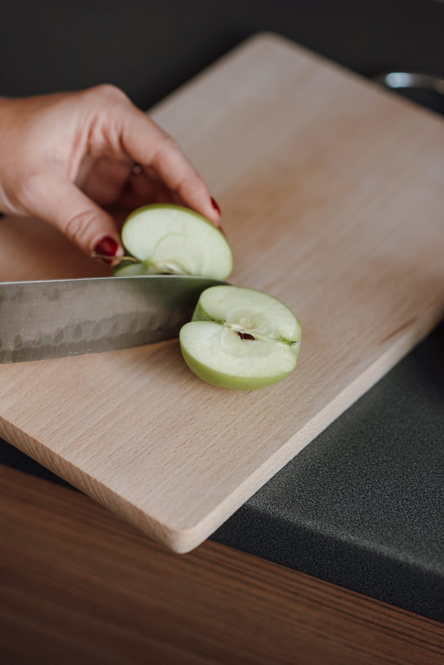 unrecognizable woman cutting apple in kitchen