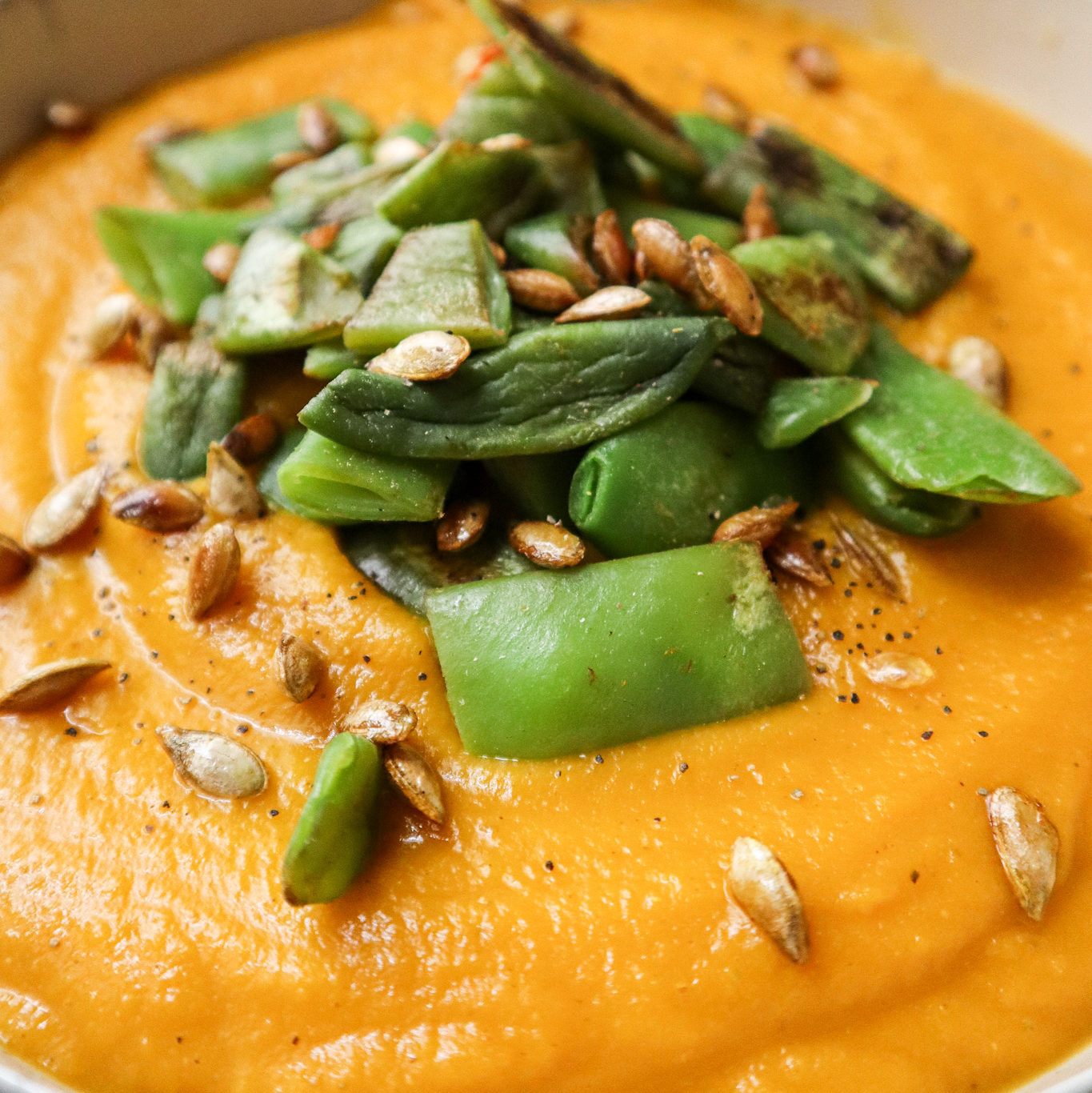 spiced Pumpkin And Carrot Soup with snap peas and pumpkin seeds