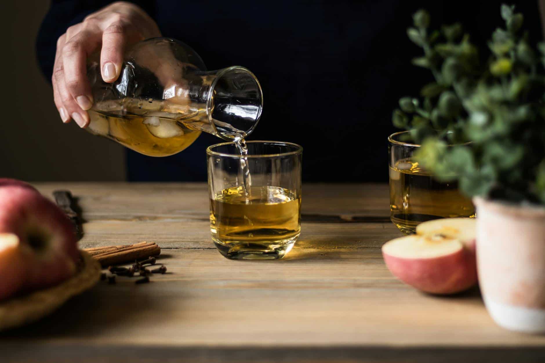 close up photo of a person pouring apple juice into a drinking beverage