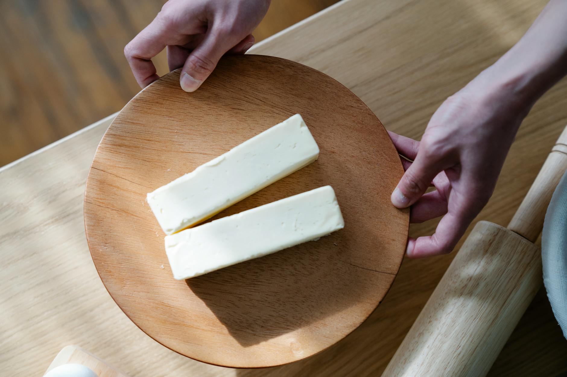 close up shot of a person holding a wooden plate with sliced butters
