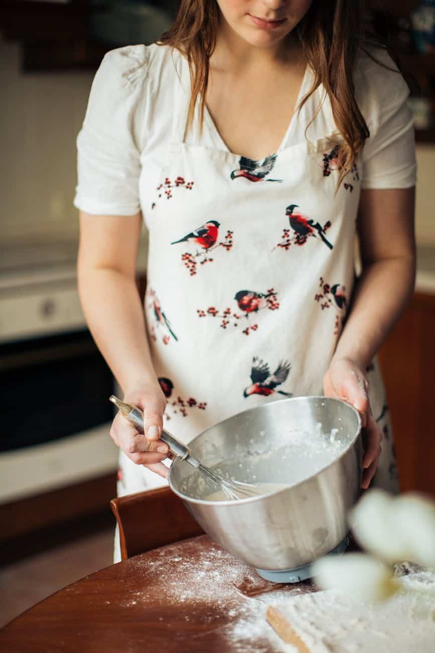 woman wearing apron holding stainless steel bowl