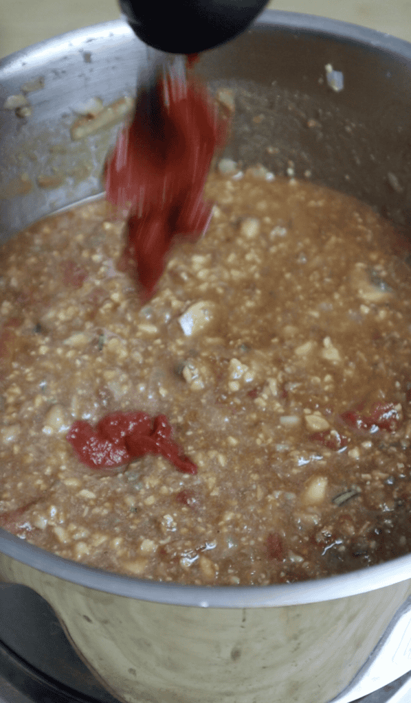 tomato paste added to a bowl of tempeh bolognese