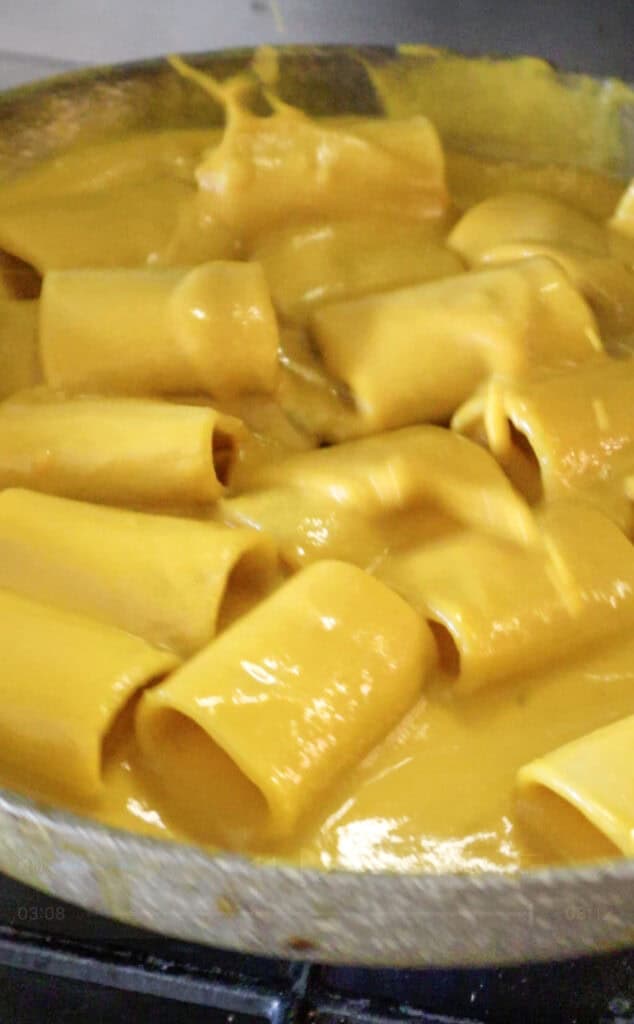 pasta with carrot sauce being tossed.