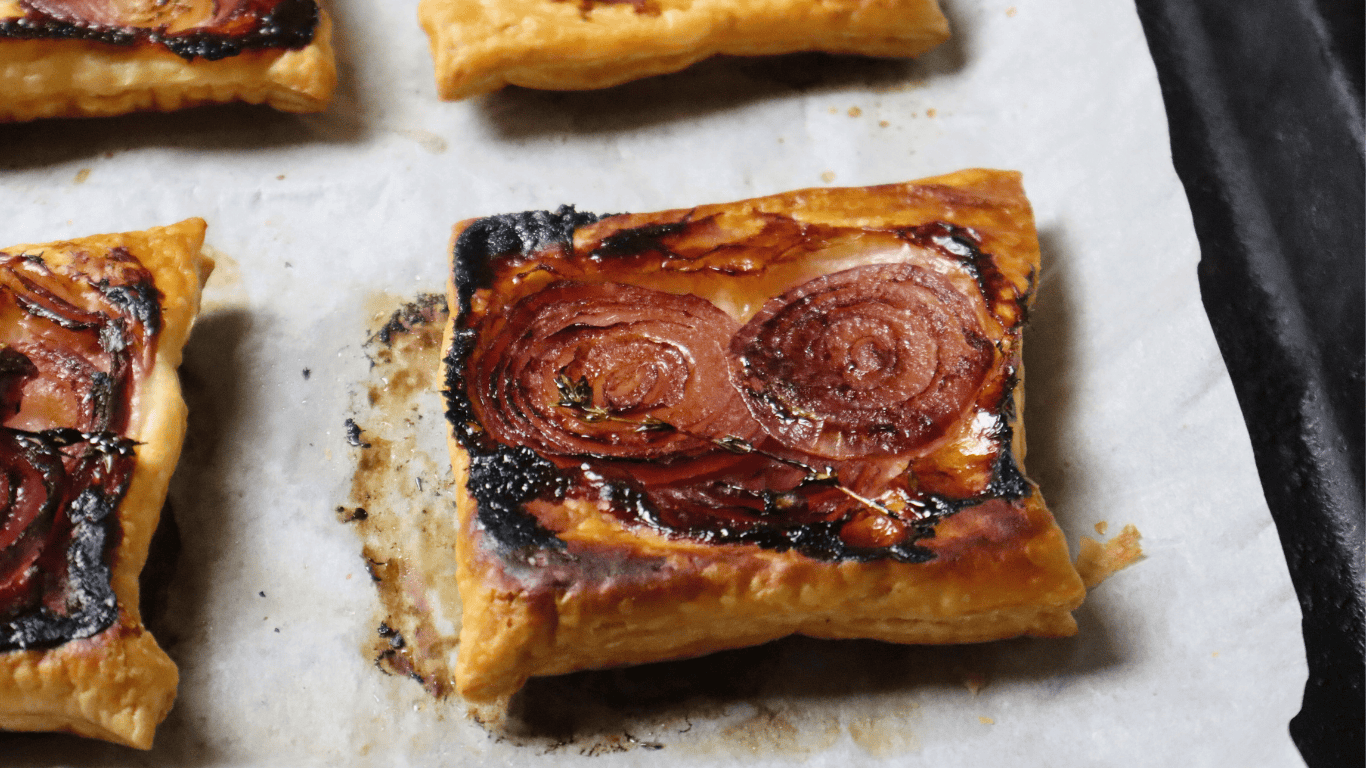 onion puff pastry tarts on baking paper